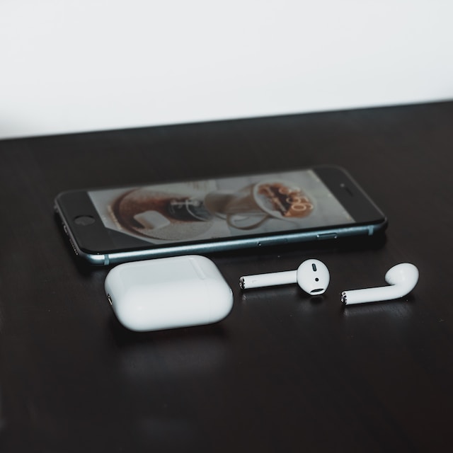 white earbuds with case on table with phone